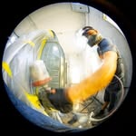 Fisheye view of technician spray painting a panel